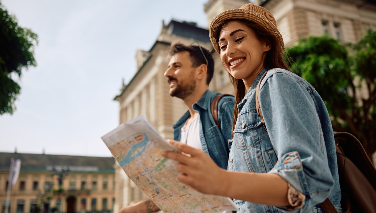 Dois turistas a passearem felizes e senhora a ver um mapa