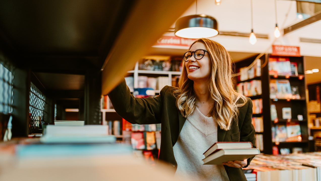 Menina a escolher livros numa biblioteca