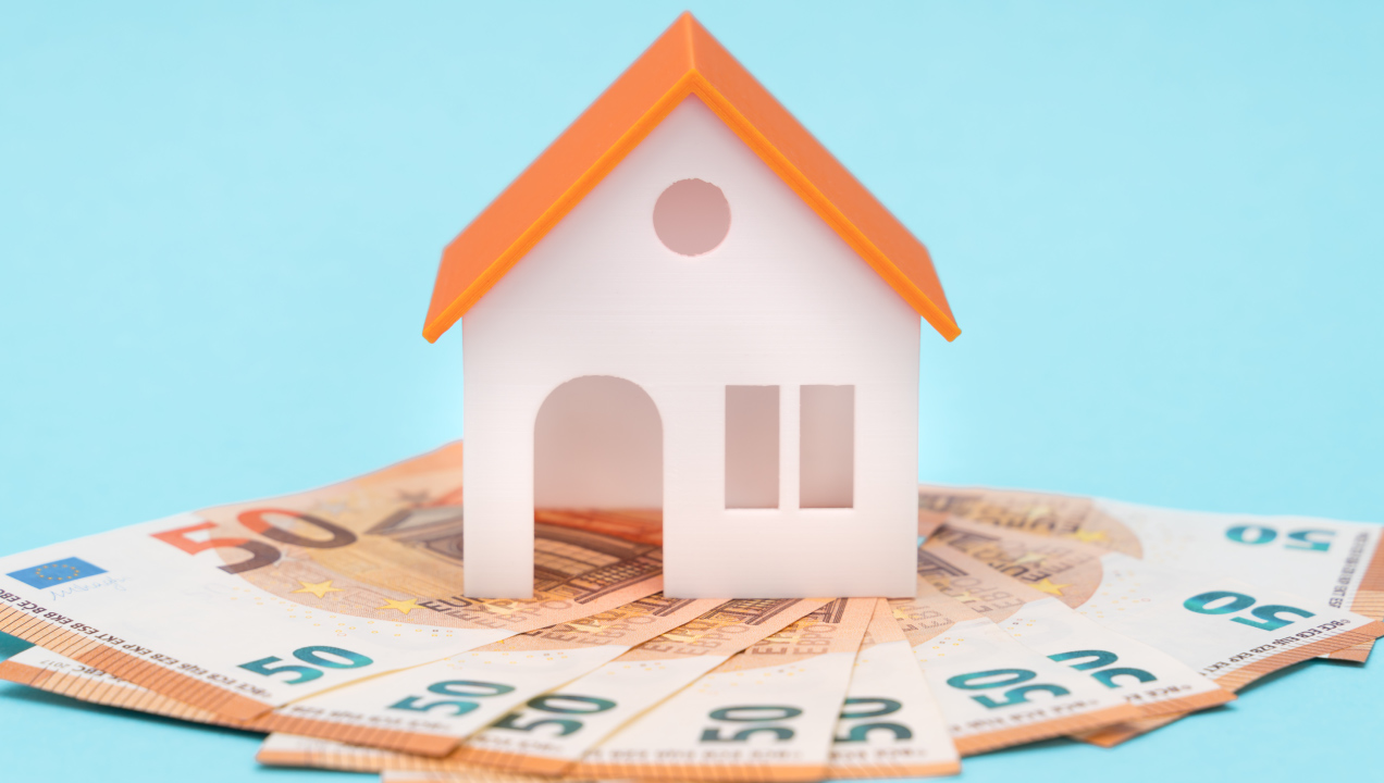 casa em miniatura sobre notas de euro dispostas em leque