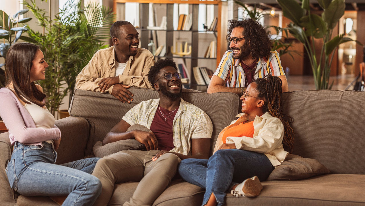 Grupos de pessoas na sala de estar de uma casa sentadas no sofá a conviver