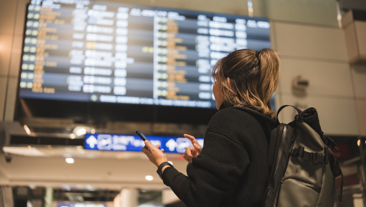 Mulher no aeroporto, vai viajar e olha para voos