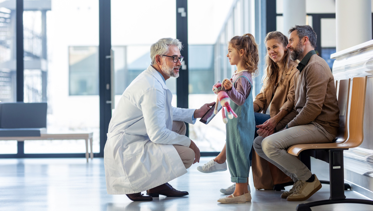 Médico a conversar com uma criança e com os pais da mesma