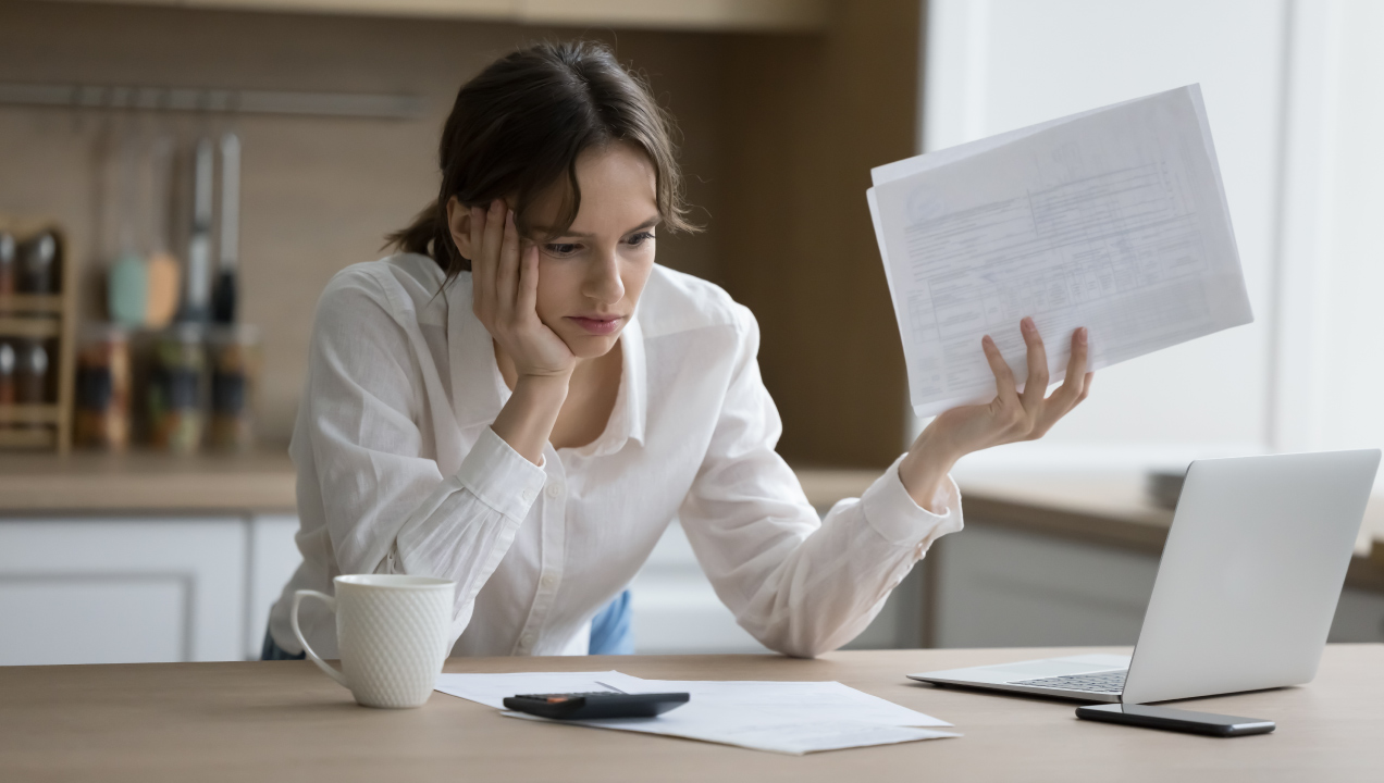 Mulher mostra frustração enquanto calcula crédito com folhas na mão