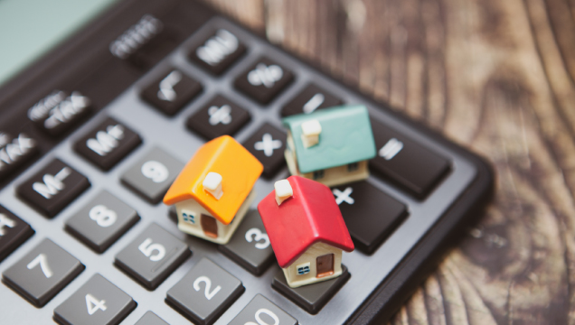 3 casas miniatura sobre uma calculadora de bolso