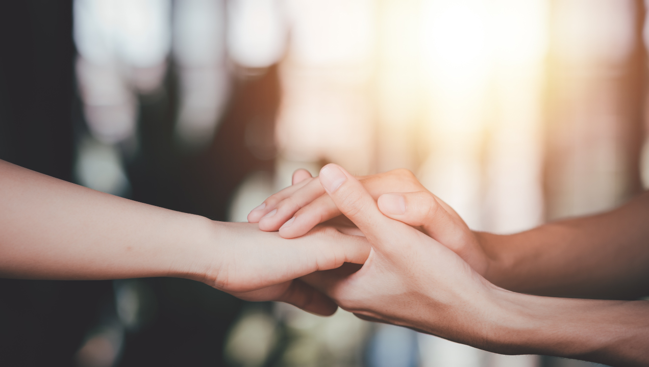 Adulto a segurar mão de criança num jogo de tabuleiros com peças de mandeira de casas