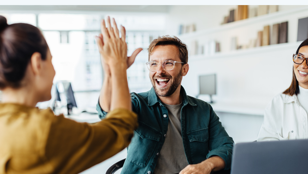 Três colegas num escritório felizes, senhora e senhor estão a comemorar a bater aos mãos