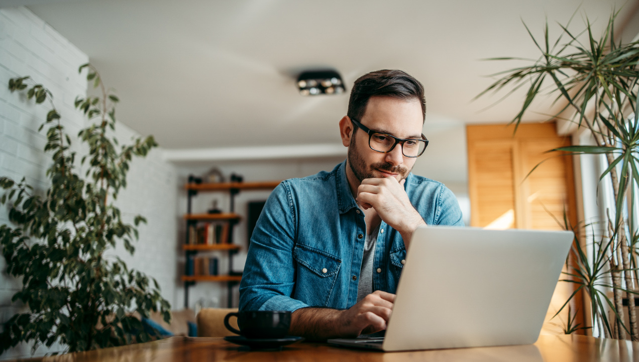 homem sentado à mesa com computador portátil
