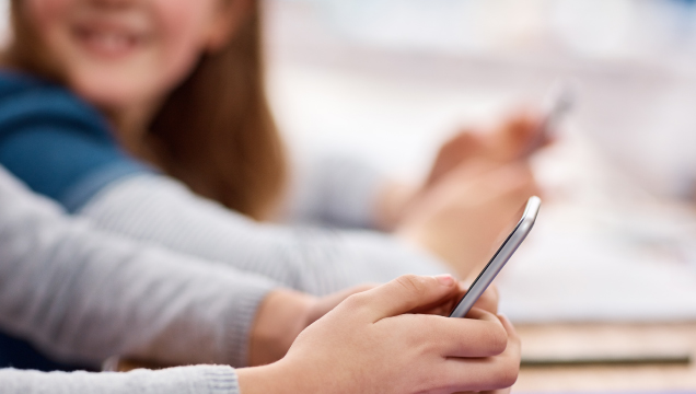 crianças na escola a segurar telemóveis na sala de aula