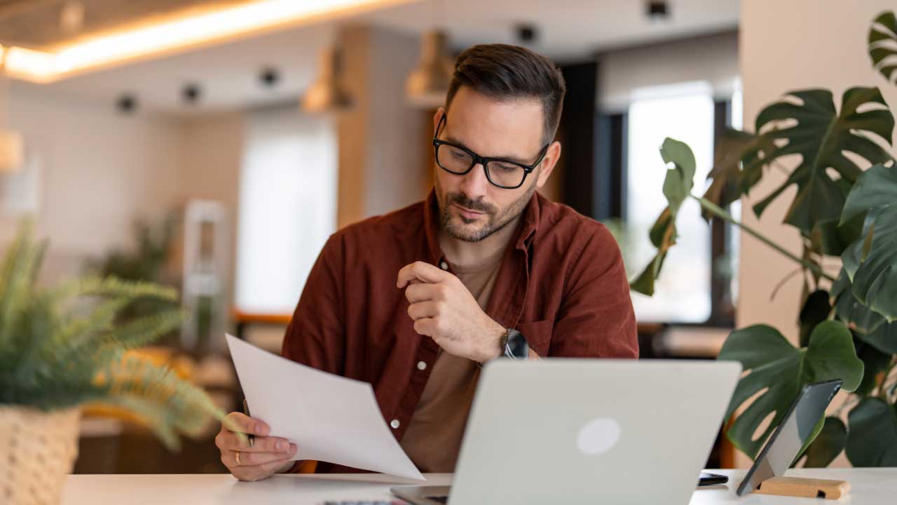 senhor com computador e a ler um documento