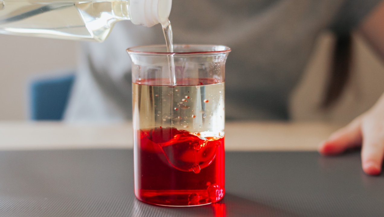 Criança com copo de laboratório a fazer uma experiência de lava caseira