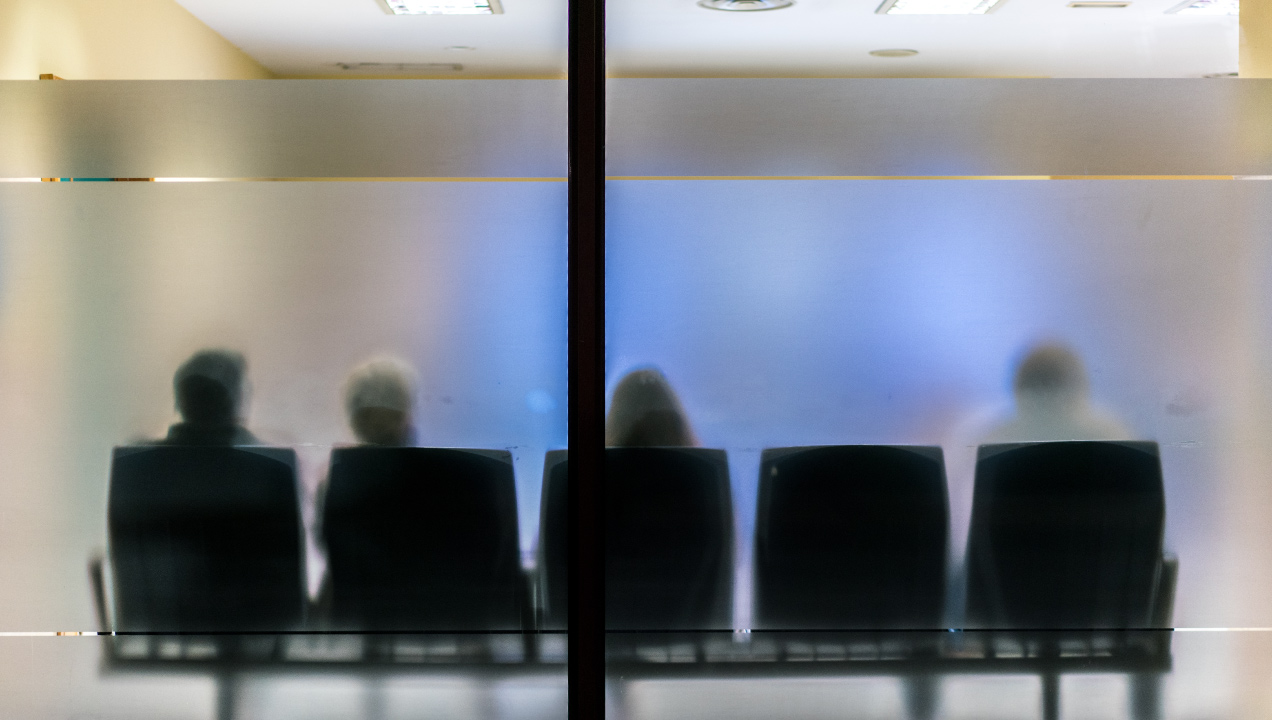 silhueta de quatro utentes a aguardar numa sala de espera