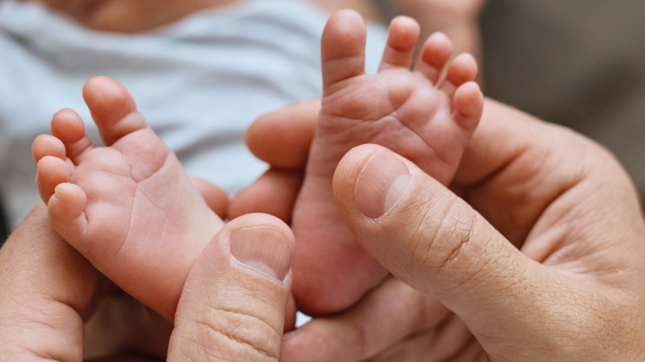 pai a agarrar carinhosamente nos pés do bébé