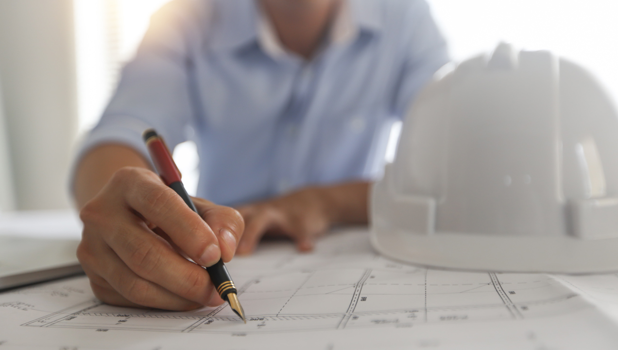 alguém usa caneta sobre uma planta de construção impressa