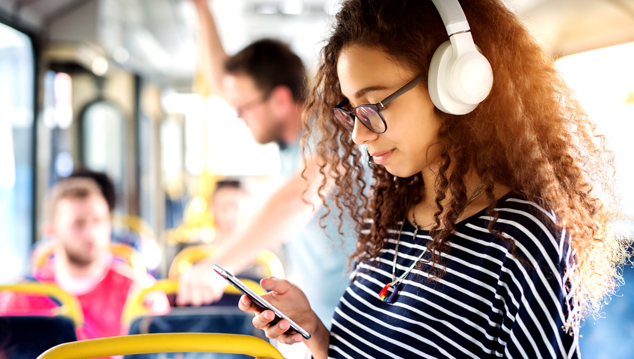 Jovem num autocarro a ouvir musica nos auscultadores e a mexer no telemóvel