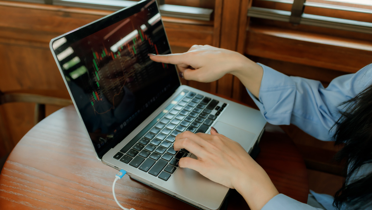 Mulher aponta para gráficos e outros dados no computador portátil