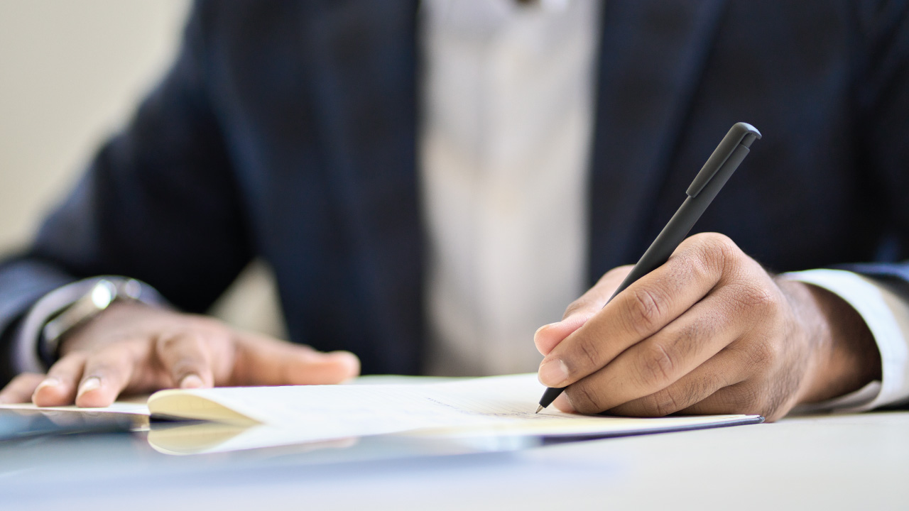 senhor a assinar documento e vestido de forma formal