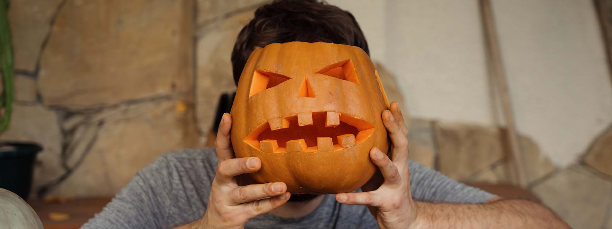 senho com uma abóbora de Halloween em frente à cara