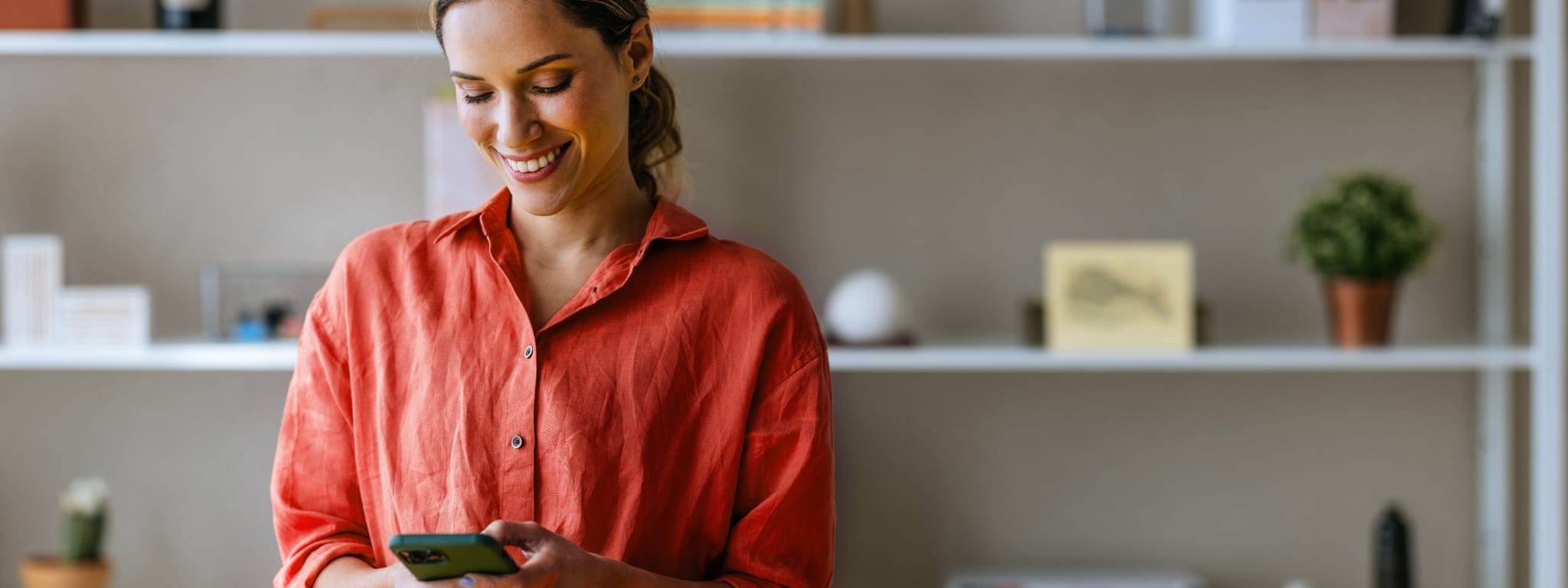 senhora com cara sorridente a olhar para um telemóvel