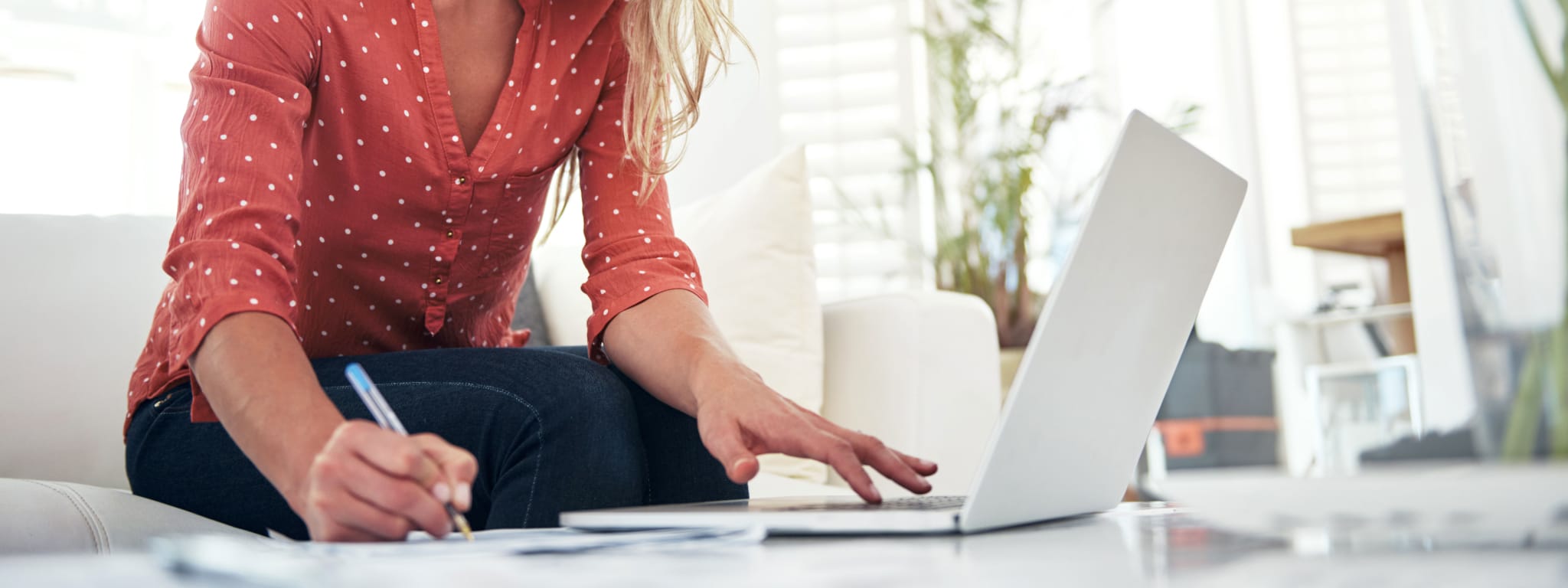 Senhora a trabalhar num computador portátil e a tirar notas