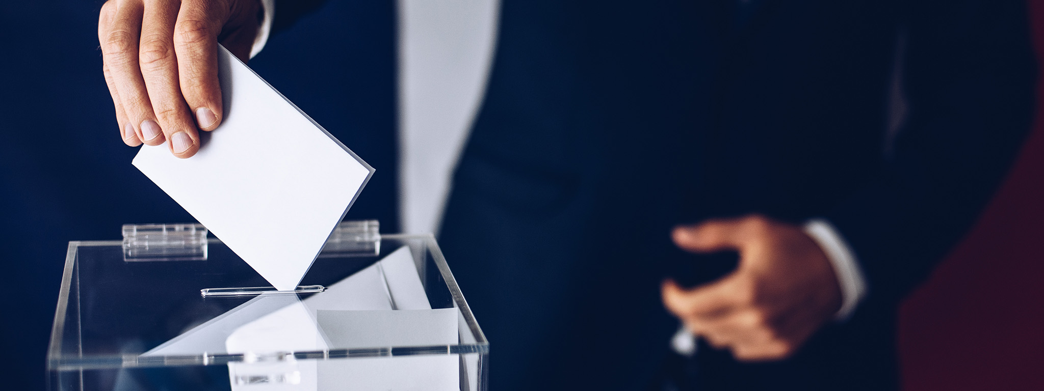 homem a colocar boletim de voto na urna