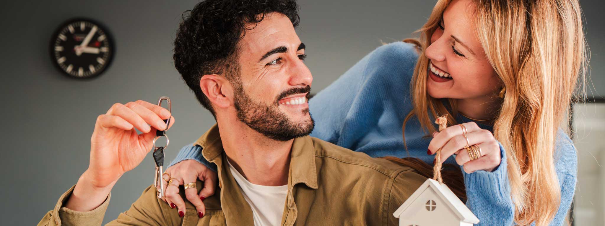 imagem de um casal feliz a segurar uma chave de casa e uma casa de madeira