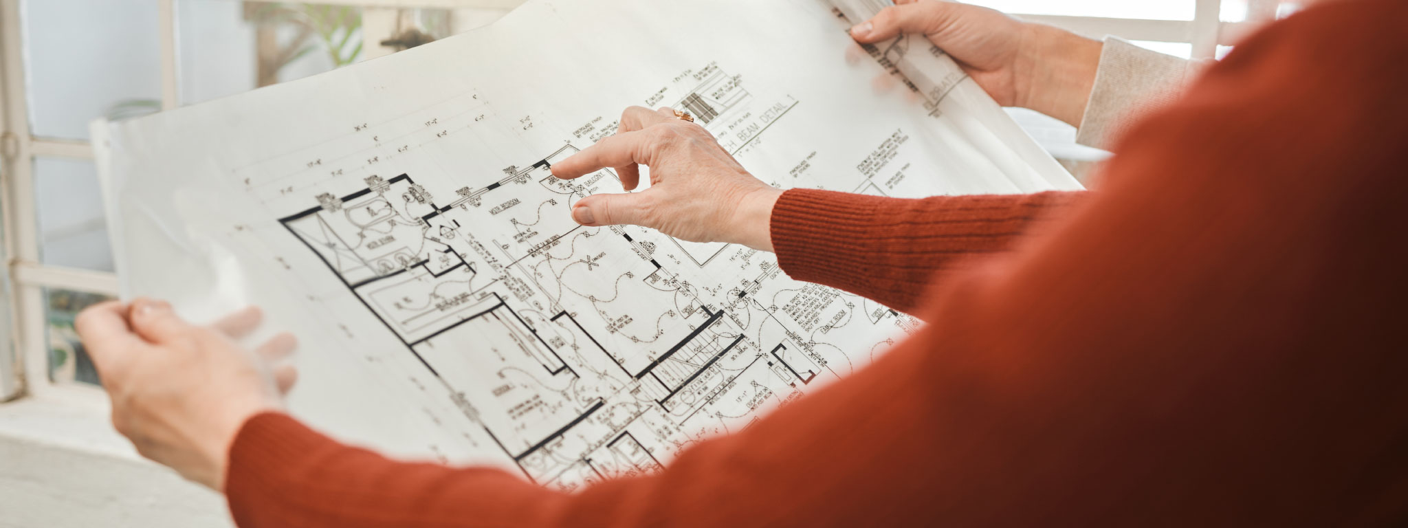  duas pessoas analisam uma planta impressa em grande formato