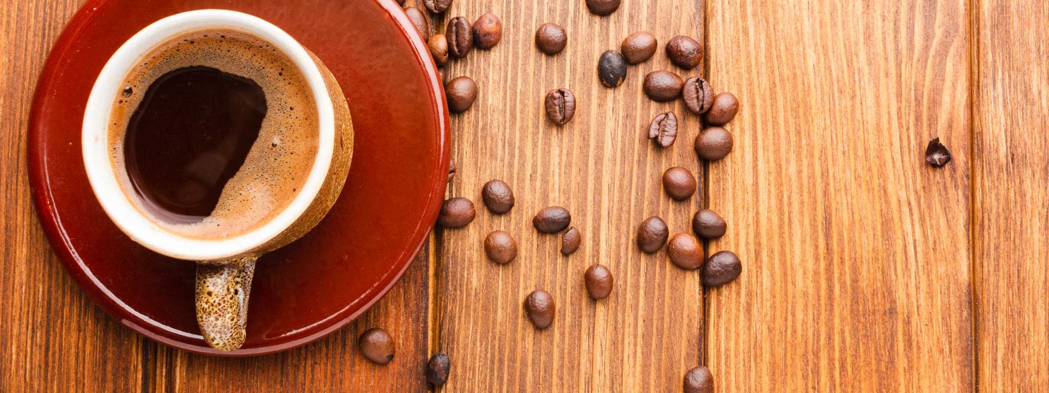 chávena com café em cima de um pires e com grãos à volta