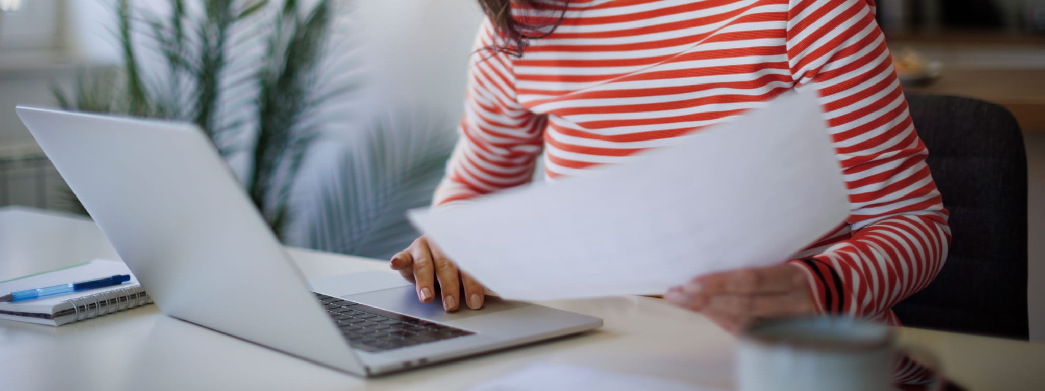 senhora em frente a computador e com uma fatura na mão