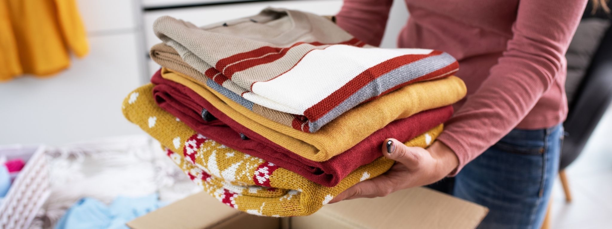 senhora a segurar um monte de roupa para doar