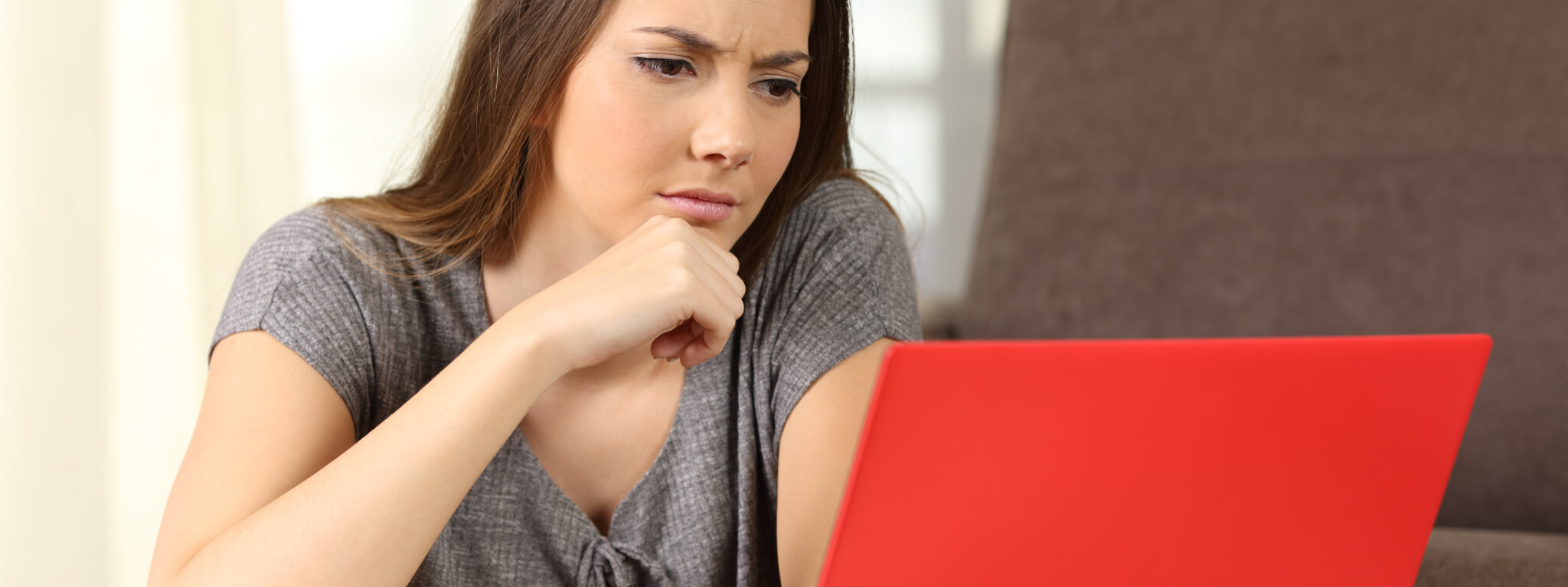 senhora em frente a um computador portátil vermelho com ar concentrado