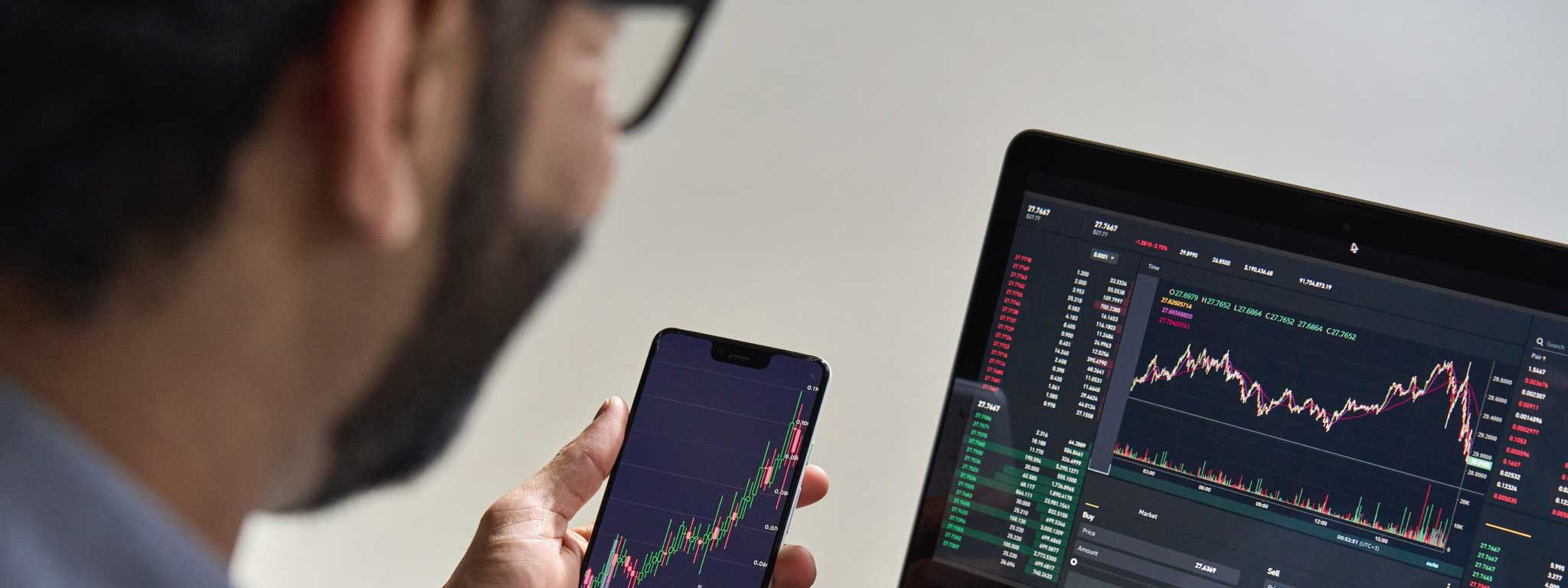 senhor a olhar para computador e telemóvel e a ver os seus investimentos