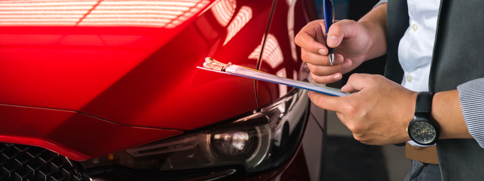 inspetor automóvel a avaliar um carro vermelho