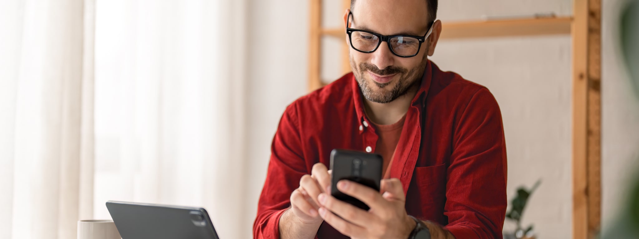 senhor com telemóvel na mão e em frente ao computador