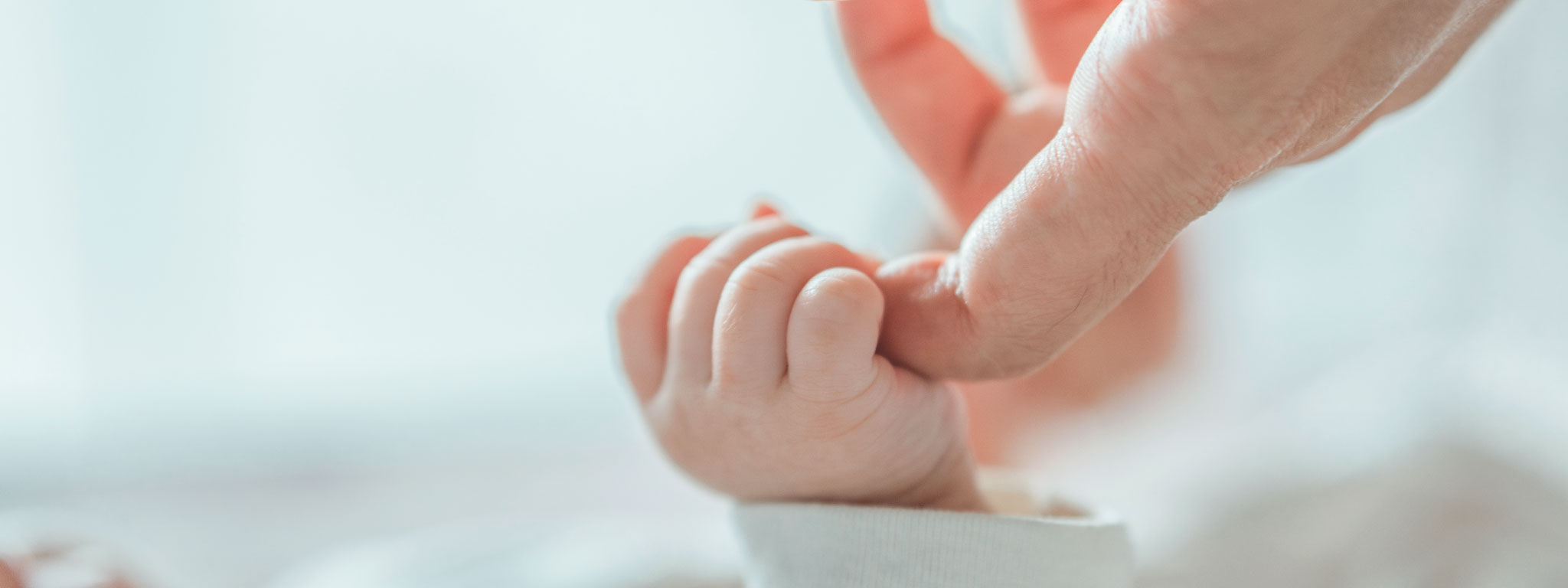 bébé a agarrar no dedo da mão do pai