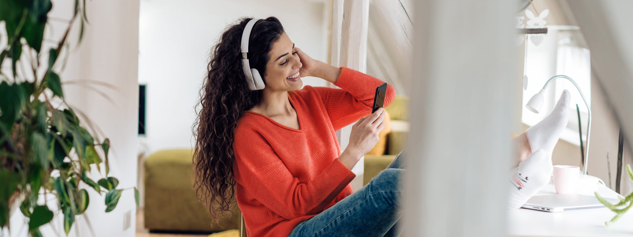 imagem de senhora com headphones a ouvir algo no telemóvel