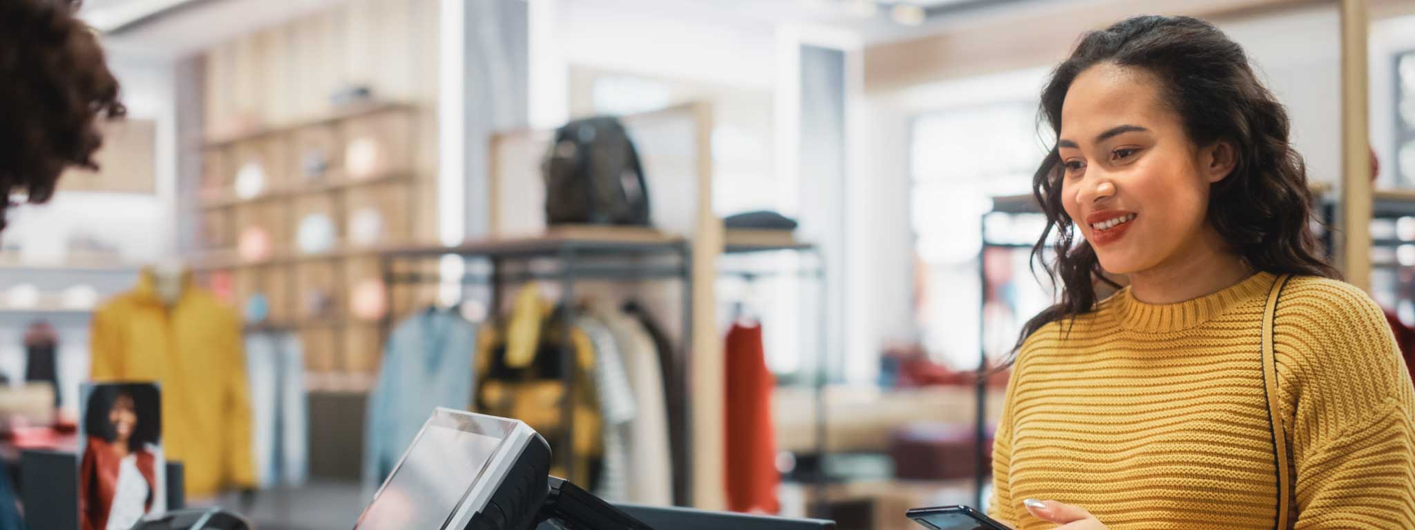 senhora a fazer um pagamento na caixa de uma loja de roupa