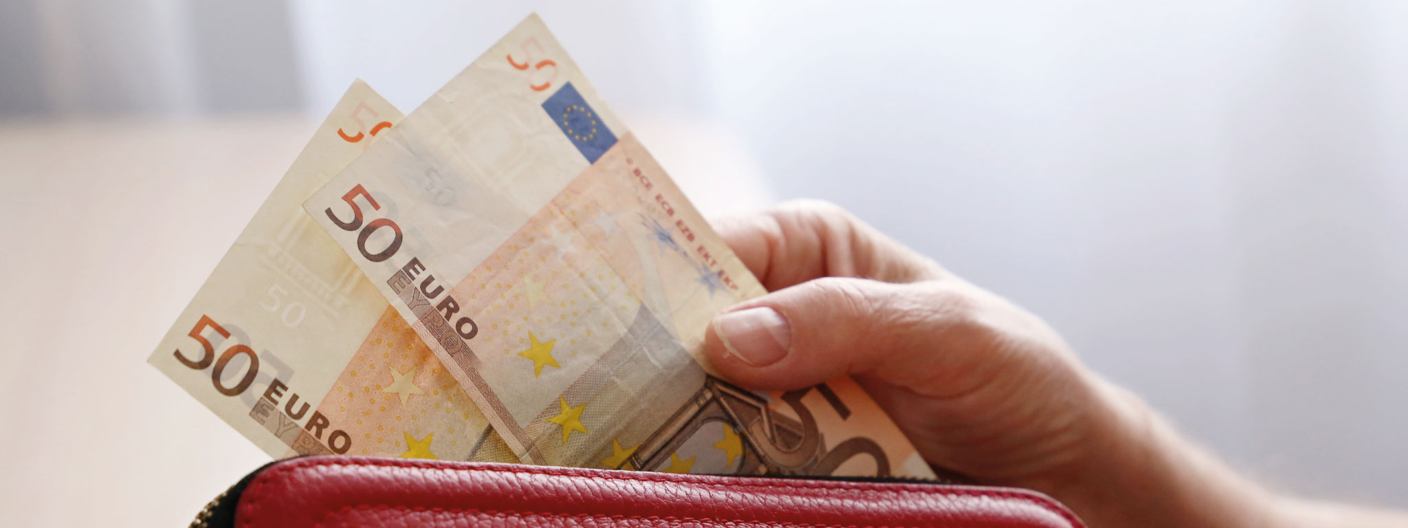 Carteira com pessoa a segurar em notas de 50 euros