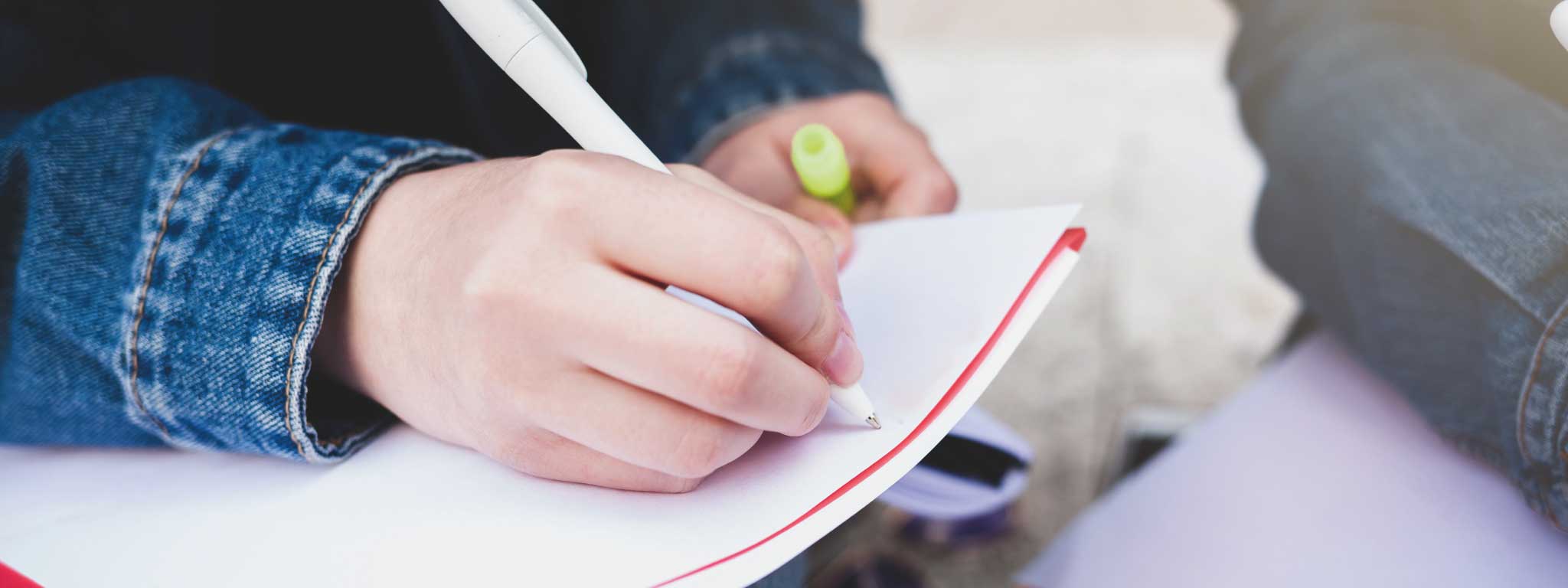 aluno a escrever no caderno com caneta