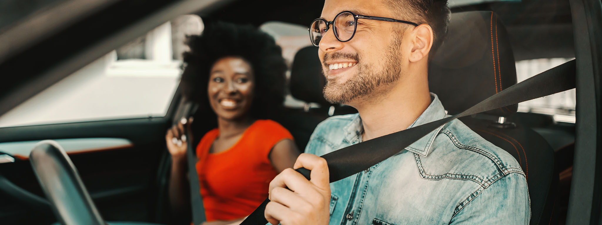 um casal num carro a colocar um cinto de segurança