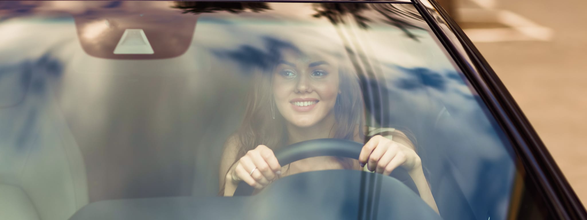 senhora a conduzir e a olhar para o seu selo do carro