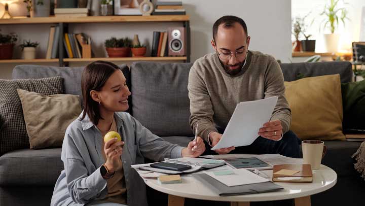 Mulher e homem a analisar um documento em papel que pode ser relativo a uma proposta de Crédito Habitação de um banco.