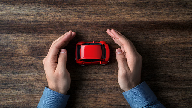 um carro pequeno vermelho protegido por duas mãos