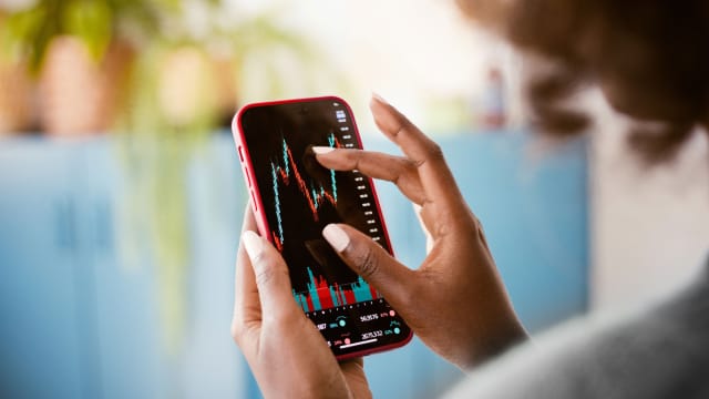 senhora ao telemóvel a investir em etf