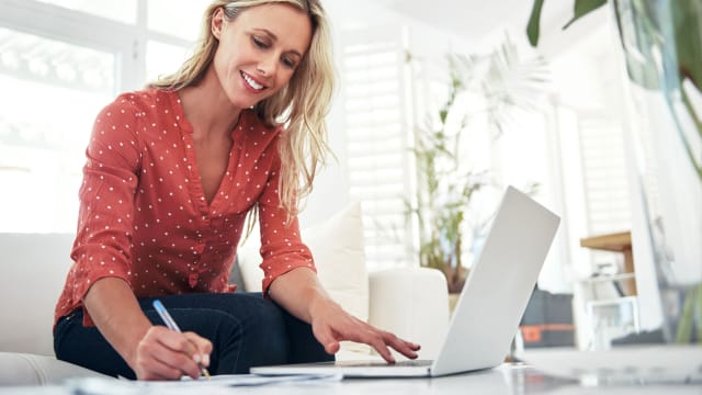 senhora a olhar para computador e a tirar apontamentos