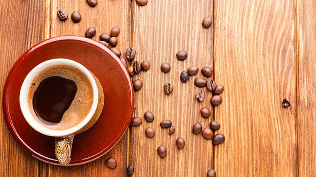 chávena com café e com vários grãos à volta
