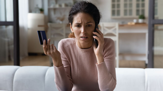 senhora ao telemóvel com cartão de crédito na mão