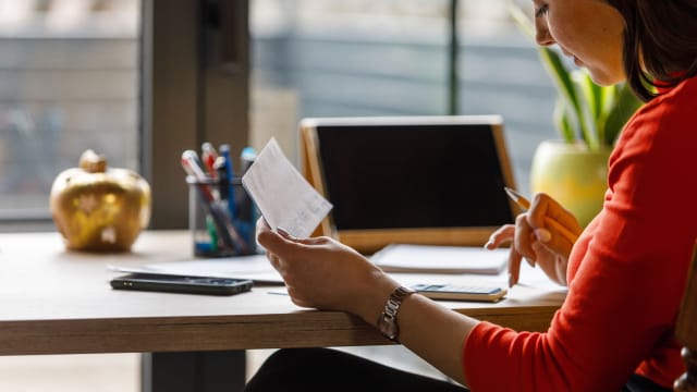 senhora a fazer calculos com uam fatura na mão