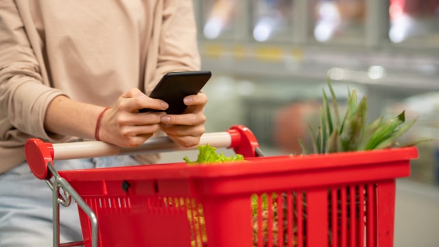 Pessoa a conduzir um Carrinho de Compras enquanto usa o smartphone
