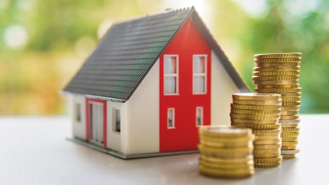 miniatura de casa com moedas em frente