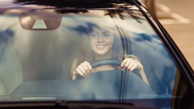 senhora com um ar feliz a conduzir o seu carro